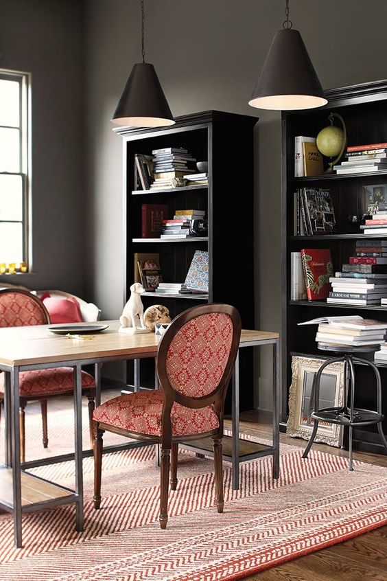 a dark and stark masculine space is balanced with red linens and red upholstery of the furniture