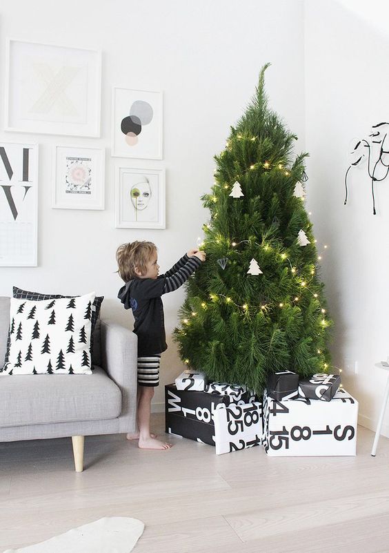 a modern Nordic tree with lights and white tree-shaped ornaments plus geometric ones