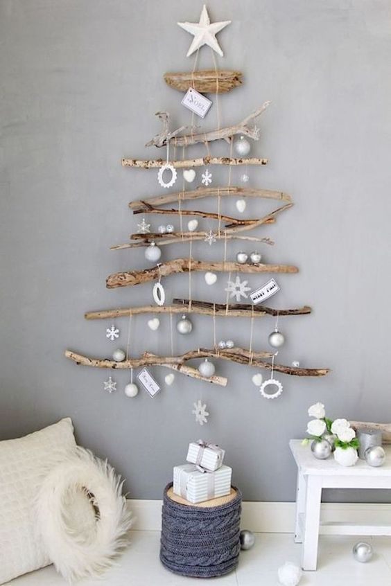 A natural wall mounted Christmas tree of various branches and with white and silver ornaments hanging down