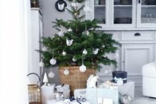 13 a small Christmas tree with lights and white ornaments plus a basket for a modern feel