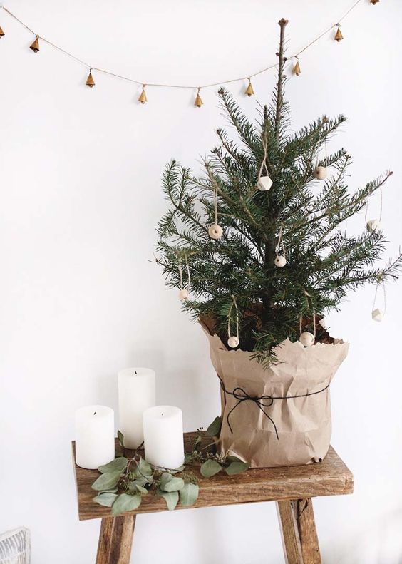 a small Christmas tree with wooden ornaments wrapped into kraft paper for a super natural feel