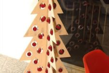 15 a plywood Christmas tree with holes and little red ornaments hanging in them for a minimalist or Scandinavian space