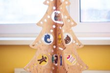 16 a plywood Christmas tree with holes of various sizes and ornaments hanging in them for a fun and creative look