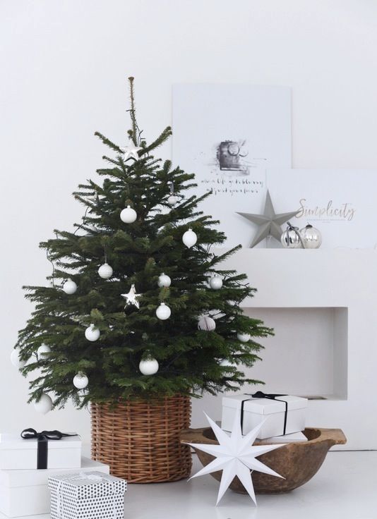 a small tree in a basket styled with white ornaments screams Scandinavian or minimalist
