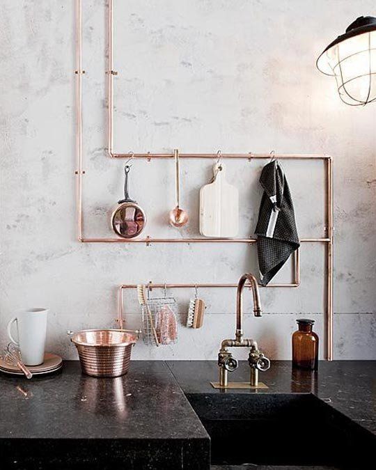 exposed copper piping doubles as utensil storage in this industrial kitchen