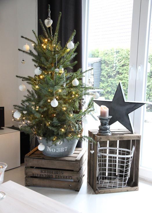 a small tree in a galvanized bucket used as a tree base with lights and white ornaments is a great rustic idea for Christmas