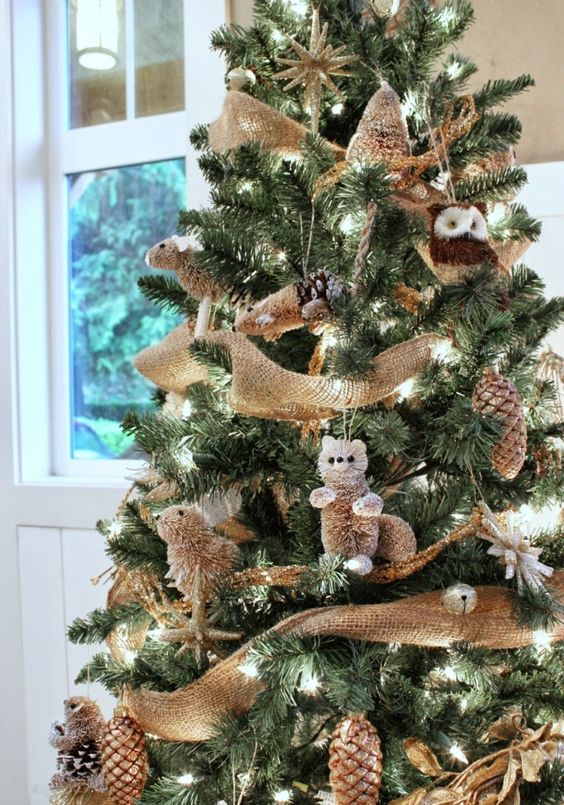 fake animal ornaments, gilded pinecones, jingle bells and burlap ribbons bring a strong rustic feel to the tree