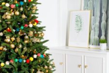 17 gold ornaments and a colorful pompom garland over the tree is a fun and whimsy idea for Christmas