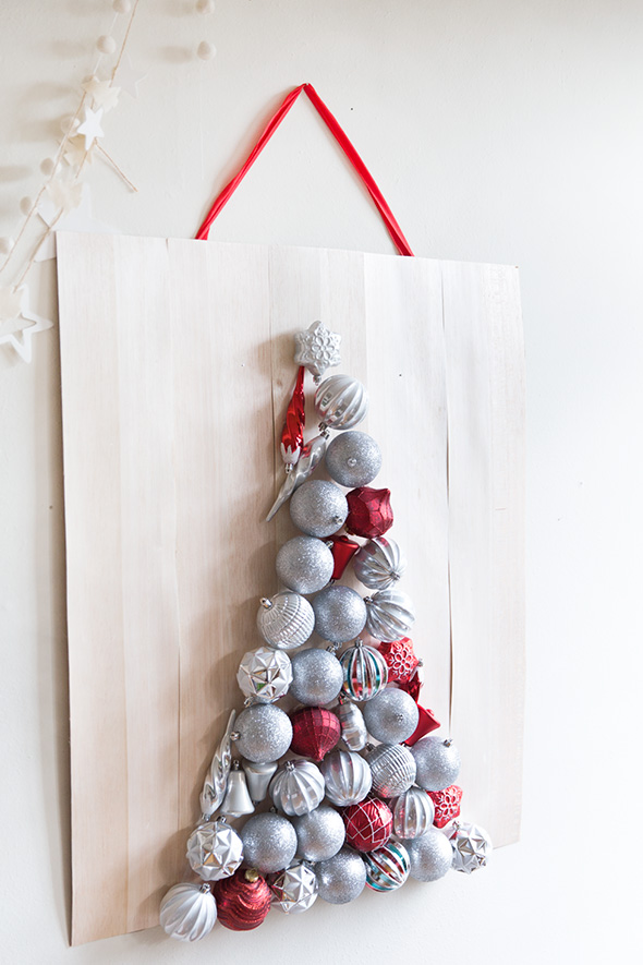 take a plywood sheet and attach some Christmas ornaments to it forming a Christmas tree and hang it on the wall