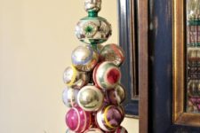 19 a cool vintage Christmas ornament tree placed on evergreens is a cool decoration for a shelf or a mantel