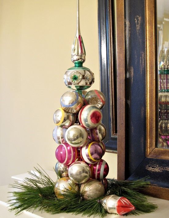 a cool vintage Christmas ornament tree placed on evergreens is a cool decoration for a shelf or a mantel