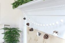 19 a snowy pinecone and pompom garland is great for decorating a fireplace, add a fresh greenery garland on top