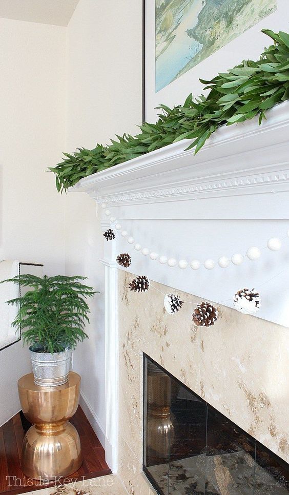 a snowy pinecone and pompom garland is great for decorating a fireplace, add a fresh greenery garland on top