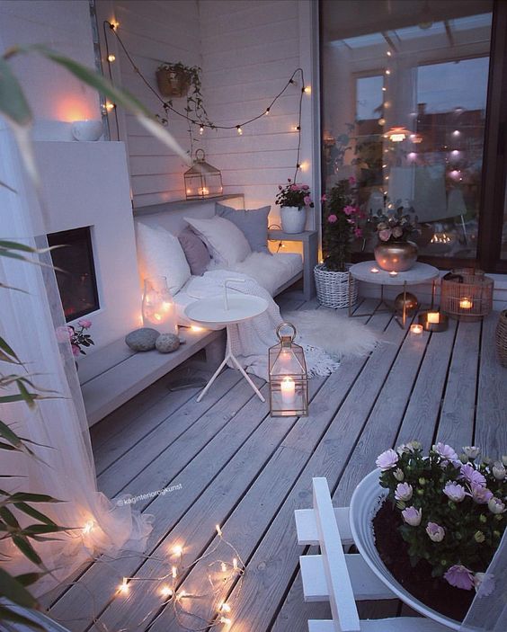 a super cozy winter terrace with a built-in fireplace, a bench, lights, candles, lanterns, potted flowers
