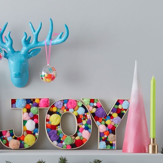 a fun and colorful Christmas decoration of letters filled with colorful pompoms of various sizes