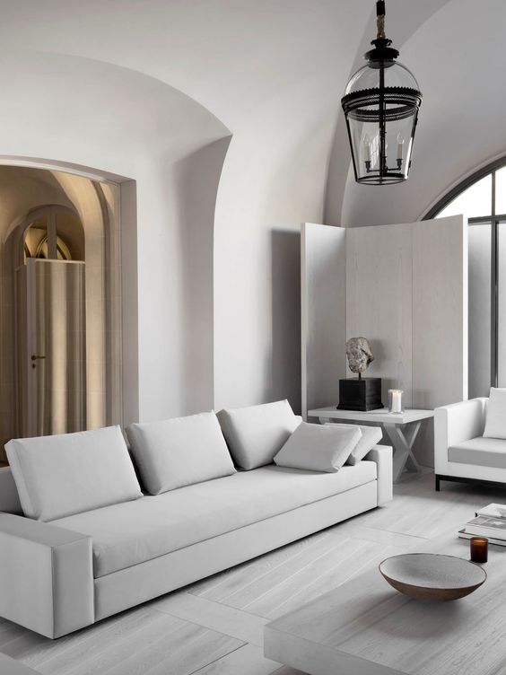 A neutral minimalist living room with clean lined furniture and an accent lamp mixing modern and vintage