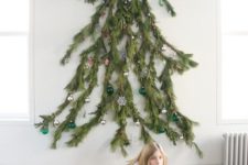 20 a wall-mounted Christmas tree featuring a natural silhouette and made of real branches, decorated with various ornaments