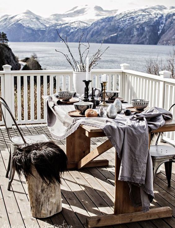 a winter terrace with a dining zone, a wooden table and mismatching chairs covered with faux fur