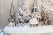 21 a mantel covered with cotton as fake snow and with a flocked mini tree and snowy trees and houses