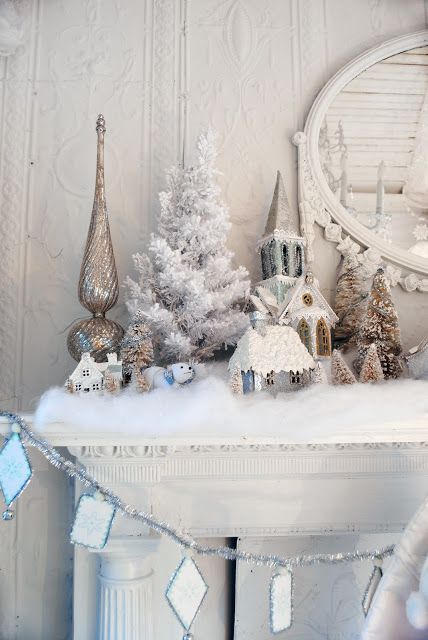 a mantel covered with cotton as fake snow and with a flocked mini tree and snowy trees and houses