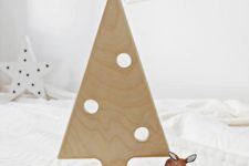 21 a small plywood Christmas tree on a stand with holes imitating ornaments and some candles