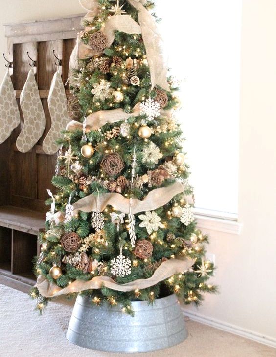 a chic rustic Christmas tree with vine and snowflake ornaments, pinecones, lights and lots of burlap plus a burlap bow on top