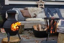 22 a wooden bench softened with blankets, pillows and faux fur, two fire bowls and firewood in a bucket for a Scandi feel