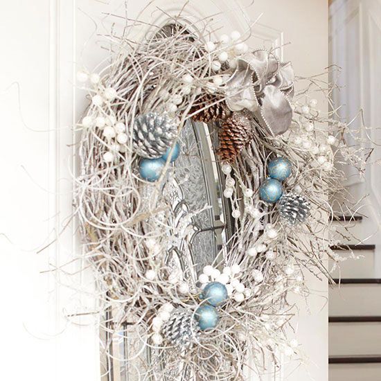 a snowy and messy holidya wreath with vines, pinecones, fake berries, ornaments and a ribbon bow