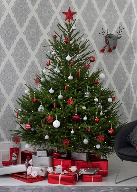 a traditional Nordic Christmas tree with white, silver, clear and red ornaments and a red star on top