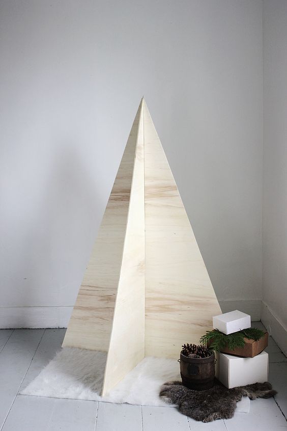 An ultra minimalist Christmas tree of plywood with no decor, just some gifts and faux fur
