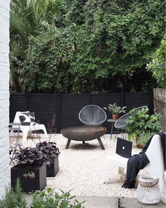 a Scandinavian terrace in black and white, with potted greenery and a fire bowl