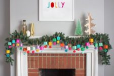 24 an advent calendar made of colorful boxes and pompoms hanging ona  lush evergreen garland