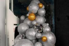 24 an oversized Christmas tree composed of oversized silver and gold glitter Christmas ornaments or balls will make a statement