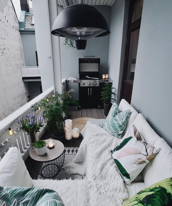 a cozy Nordic balcony with potted plants, printed textiles and a grill - all you need in one