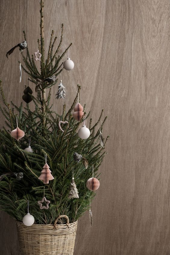 a small tree decorated with white ball ornaments and red paper ones and placed in a basket for a Nordic feel