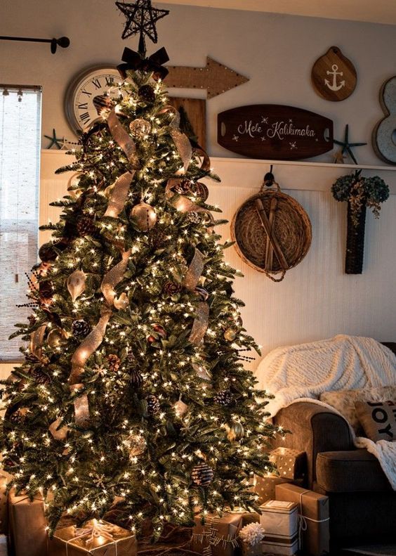 a rustic luxe Christmas tree with snowy and gilded pinecones, burlap ribbons, large metal ornaments and lots of lights