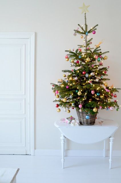 a small tree in a basket styled with super colorful ornaments and lights plus a star on top
