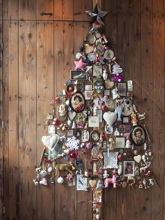 A whimsical wall mounted Christmas tree of figurines, frames, photos and various vintage stuff for a shabby chic space