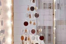 27 take a large frame, hang some yarn and form a Christmas tree of your favorite ornaments, line it up with lights