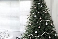 a Christmas tree with metallic and white ornaments and white felt ball garlands