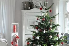 a Christmas tree with red and white ornaments and a striped basket is a cool and catchy decor idea