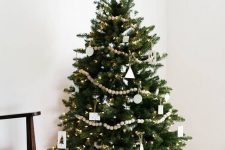 a Nordic Christmas tree with white ornaments of plywood, wooden beads and lights is a fresh and cool idea