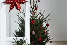 a Scandinavian Christmas tree between modern and traditional with red and white ornaments and baskets around