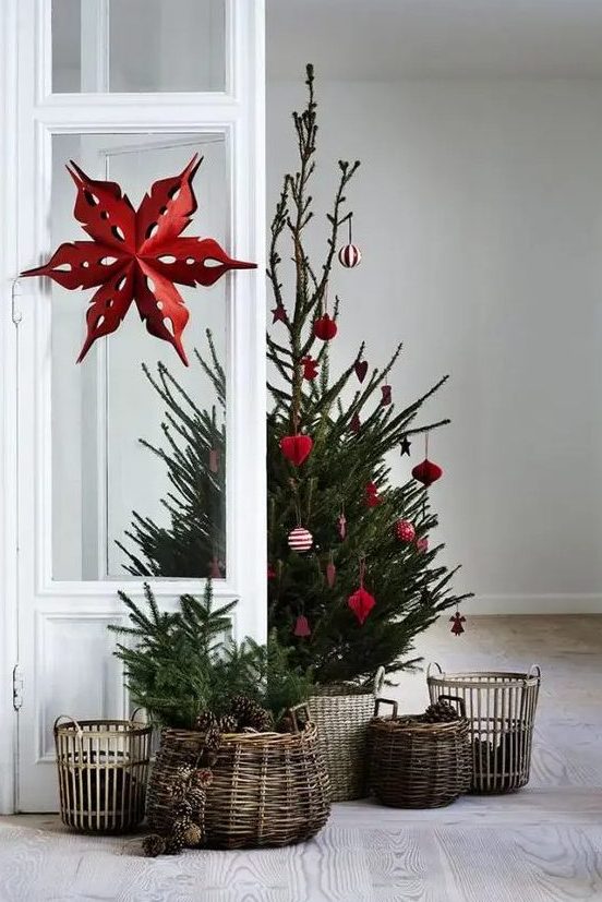 a Scandinavian Christmas tree between modern and traditional with red and white ornaments and baskets around