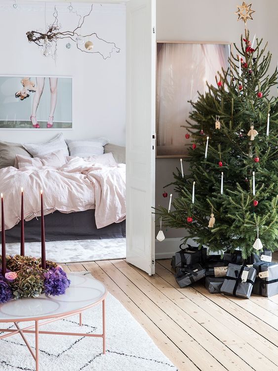 a Scandinavian Christmas tree styled with red ornaments and candles is a cool and lovely idea for a Nordic space with a touch of vintage