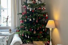 a Scandinavian Christmas tree with red and white ornaments, lights and pompoms is a cool and catchy decoration
