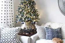 a beautiful vintage-inspired Christmas tree decorated with lights, navy ornaments, beaded garlands, snowflakes and put into a lovely pot
