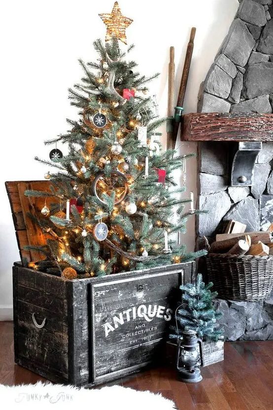 a black wooden box with a Christmas tree, a basket with firewood and a mini tree in a crate for a rustic feel