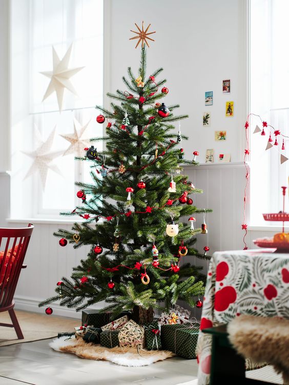 a bright Scandinavian Christmas tree with red and wooden ornaments and banners is a super cool idea