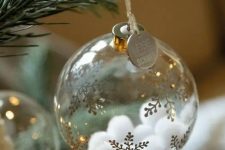 a clear glass Christmas ornament with gold snowflakes and white pompoms inside plus a coin is a cool glam idea to rock